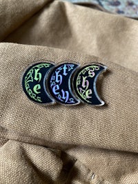 three enamel pins with the words'be the moon'on them